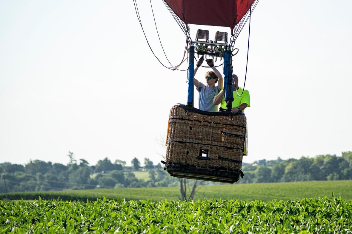 A small group boarding a balloon basket at sunrise