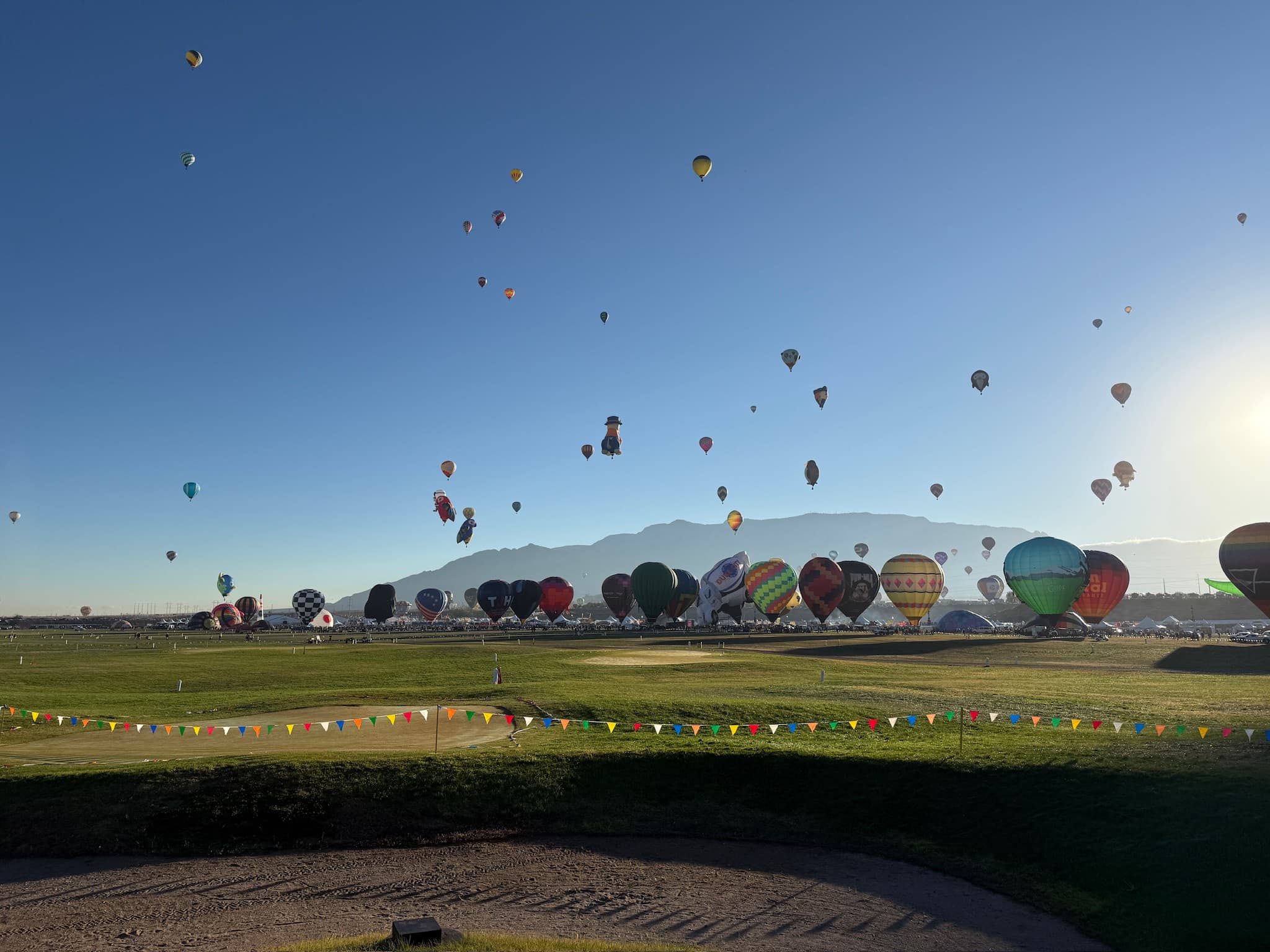 Hot air balloons inflating and lifting off at a balloon festival at dawn